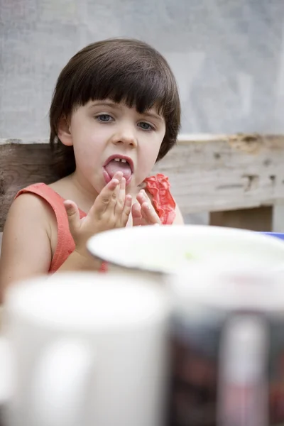 Little cute girl lick her fingers after dinner — Stock Photo, Image