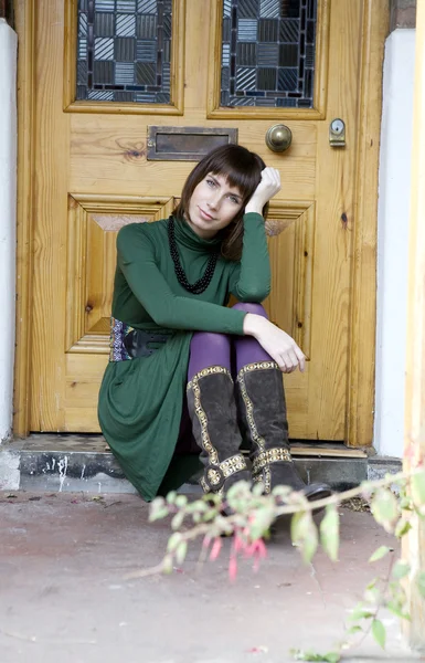 Retrato joven atractiva mujer sentada en la puerta — Foto de Stock