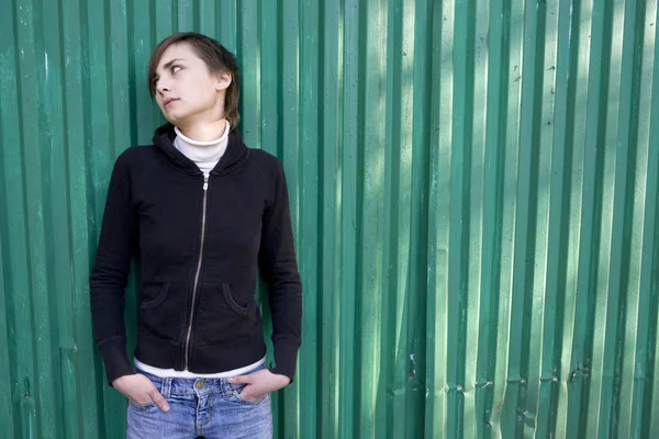 Lonely sad girl standing at green wall. — Stock Photo, Image