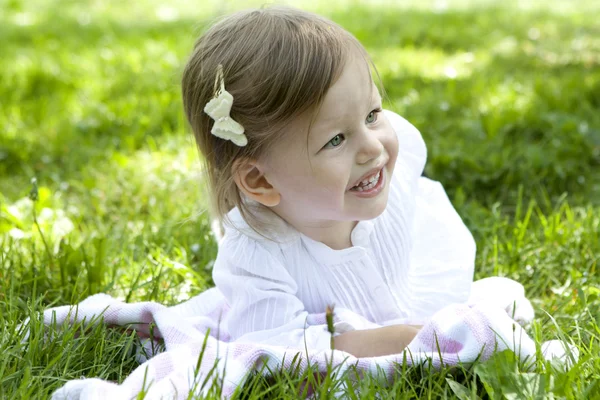 Lachen meisje twee jaar oude liggen op gras — Stockfoto