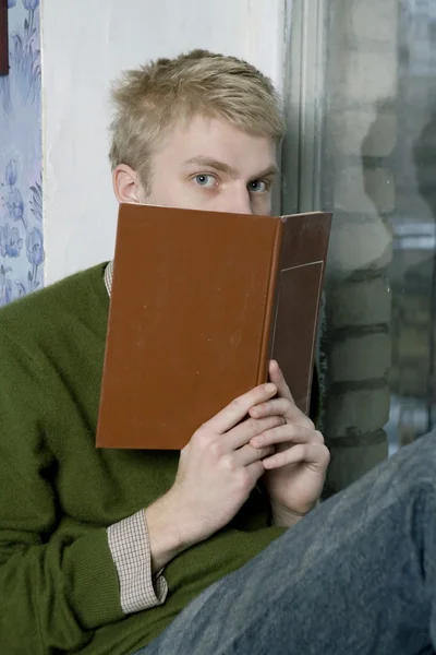 Um estudante universitário olhando através de um livro — Fotografia de Stock