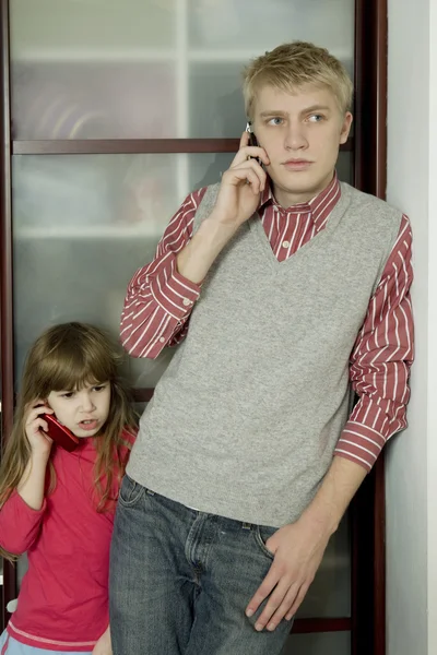 Brother and sister speaking by phones — Stock Photo, Image