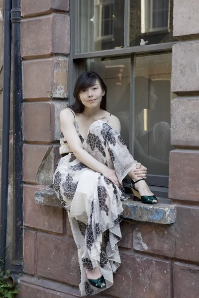 Attractive girl in fashionable dress near wall — Stock Photo, Image