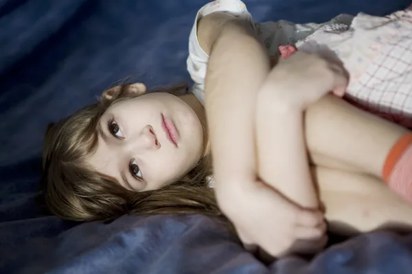 Yatakta yatan küçük üzgün kız. — Stok fotoğraf