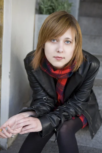 Junges attraktives Mädchen mit roten Haaren sitzt auf der Straße und wartet — Stockfoto