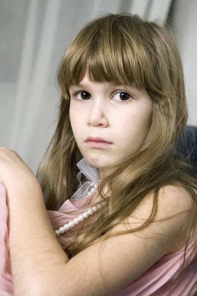 Young sad girl with brown eys sitting on sofa — Stock Photo, Image