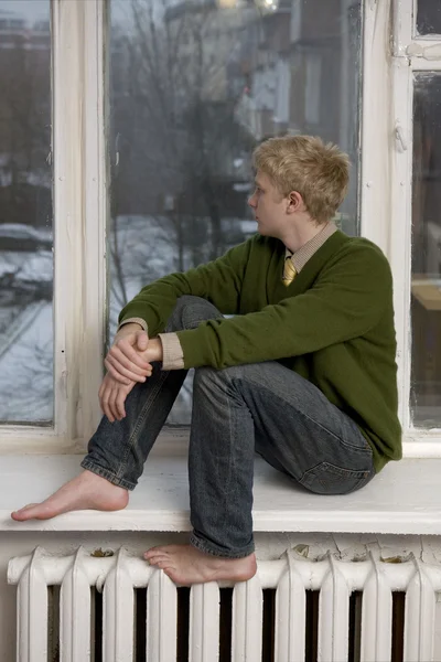 Ung man sitter på fönsterbrädan- — Stockfoto