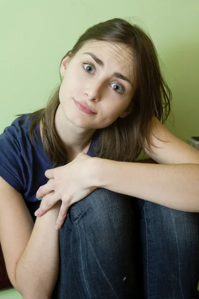 Teasing  girl sitting at the  green wall. — Stock Photo, Image