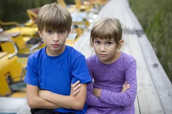 Hermano y hermana serios sentados en muelles —  Fotos de Stock