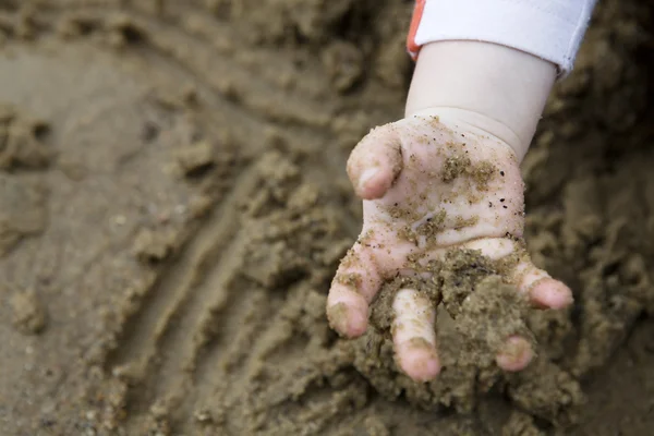 Barnets hand med sand — Stockfoto