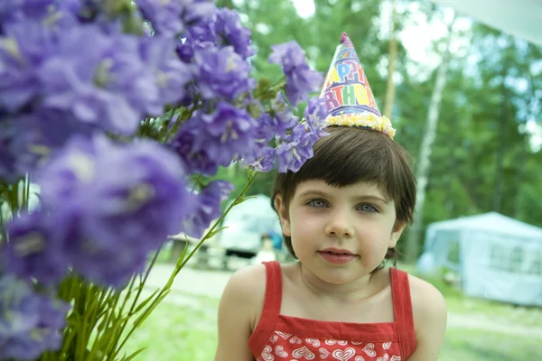 Pequena menina adorável em boné tolo sentado em flor. Aniversário — Fotografia de Stock