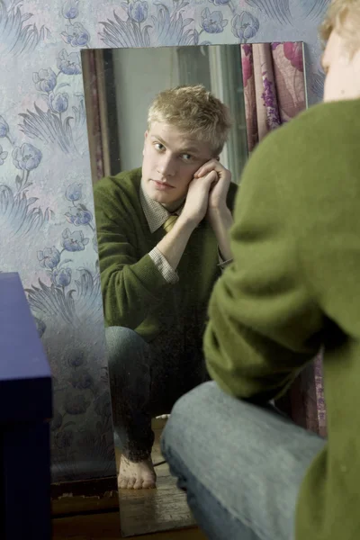 Retrato del joven hombre guapo está mirando en el espejo — Foto de Stock