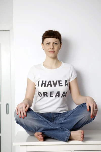 Young serious woman wearing t-shirt "I have dream" sitting on table — Stock Photo, Image