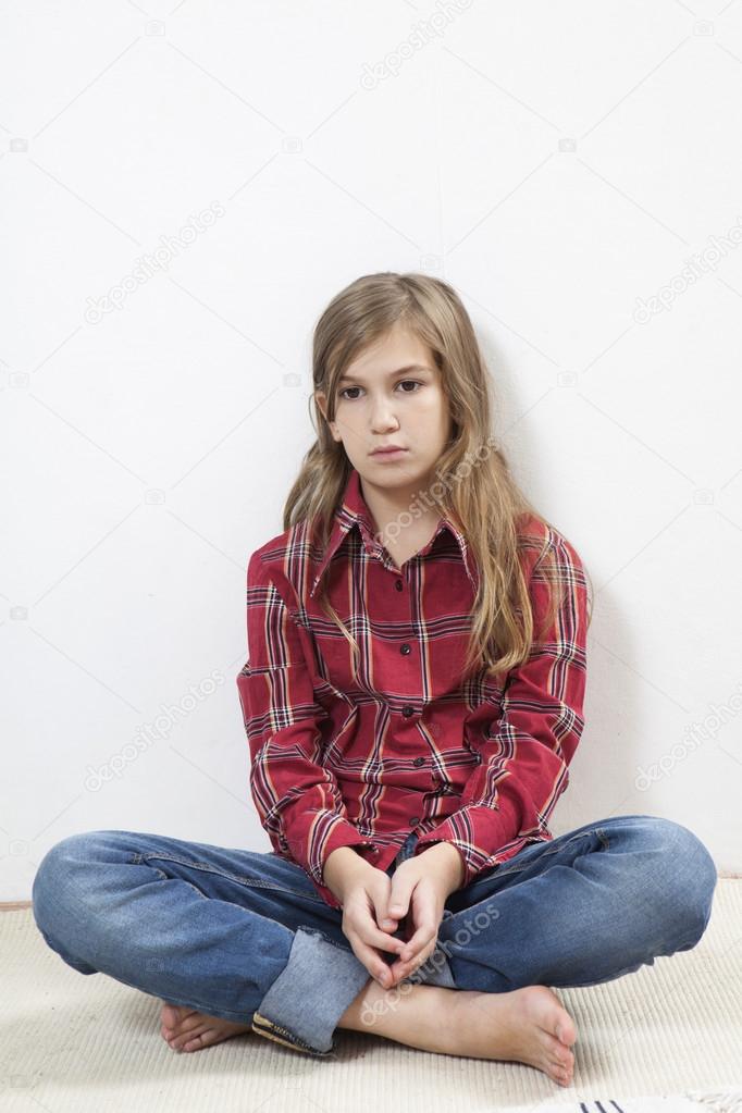 Unhappy little girl sitting on carpet.