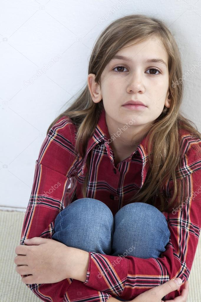 Unhappy little girl sitting on carpet.