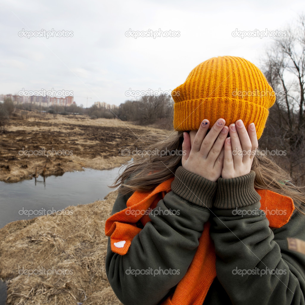 Sad teenager in orange knitten hat