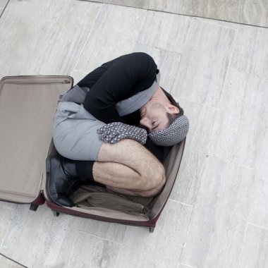 Pensive man in check cap lying in broken trunk clipart