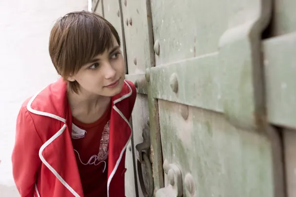 Giovane ragazza guardando attraverso la porta — Foto Stock