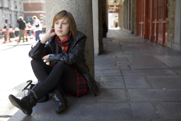 Chica atractiva joven con el pelo rojo sentado en la calle, esperando . —  Fotos de Stock