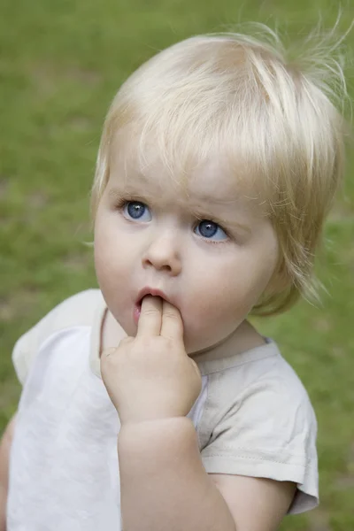 Πορτρέτο του χαριτωμένο ξανθό μωρό σοβαρές κοριτσάκι. Τα δάχτυλά της στο στόμα — Φωτογραφία Αρχείου