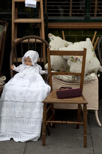 Doll in white hat sitting on chair, Flea market, London. — Stock Photo, Image
