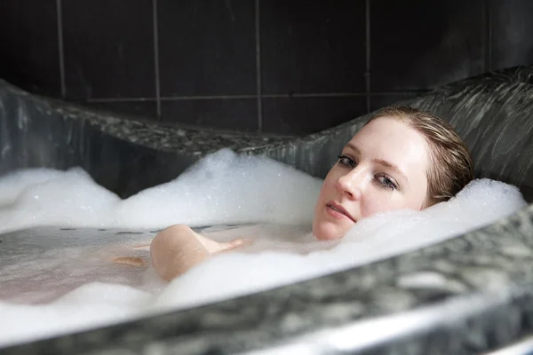 Ernstige vrouw geniet van het bad-schuim in de badkuip. — Stockfoto