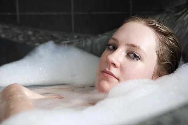 Jovem mulher séria goza da espuma do banho — Fotografia de Stock