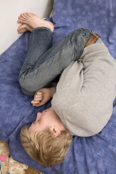 Jonge blonde verdrietig man liggend op het bed. — Stockfoto