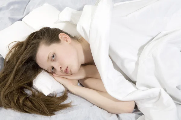 Attractive thoughtful brunette curl woman with a pillow — Stock Photo, Image