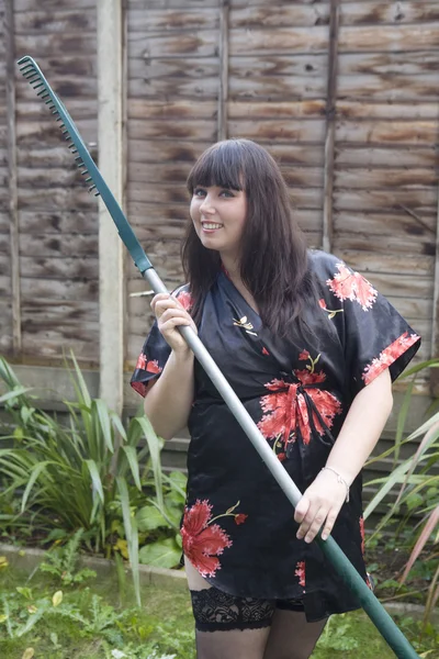 Tuinman ontspannen houden een hark. vrouw in sexy jurk — Stockfoto