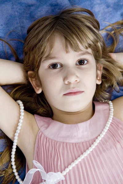 Closeup portrait of desperate little girl lying on the bed — Stock Photo, Image
