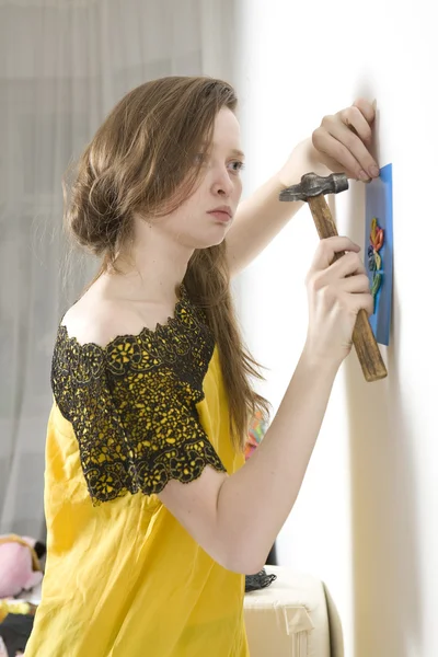 Vrouw in opengewerkte handschoenen probeert te nagel foto om witte muur. C — Stockfoto