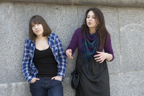 Dvě dívky mluvit u zdi z kamene — Stock fotografie
