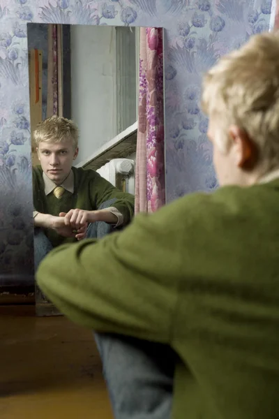 Retrato del joven hombre guapo está mirando en el espejo — Foto de Stock