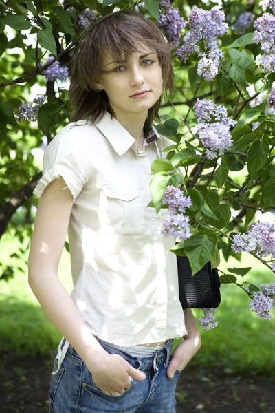 Serious brunnete woman standing nearby lilac — Stock Photo, Image