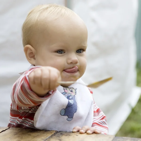 Belo bebê de olhos azuis comendo molho de maçã com uma colher isolada em branco — Fotografia de Stock