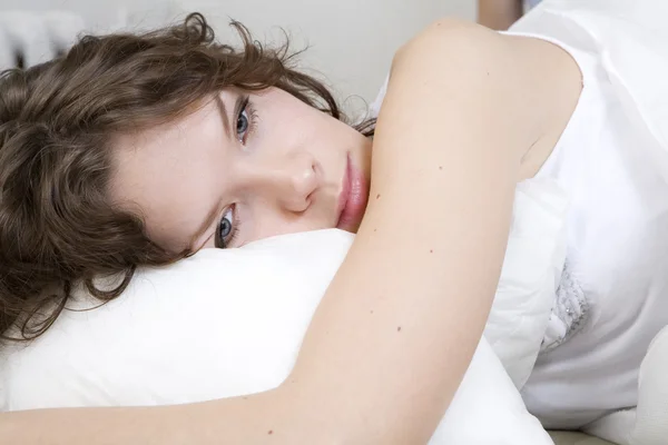 Bruneta curl žena leží na posteli — Stock fotografie