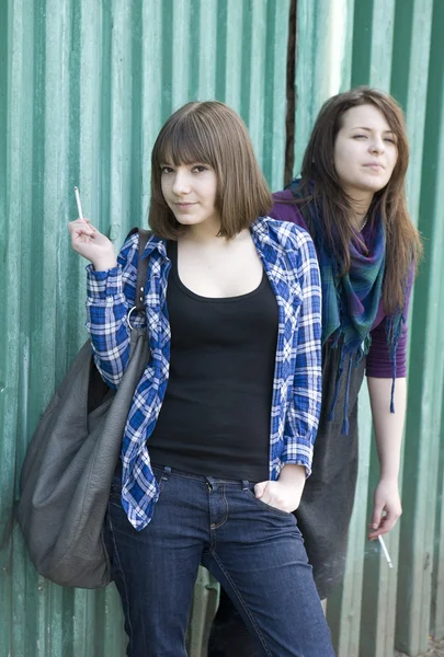 Dos chicas fumando de pie en la valla —  Fotos de Stock