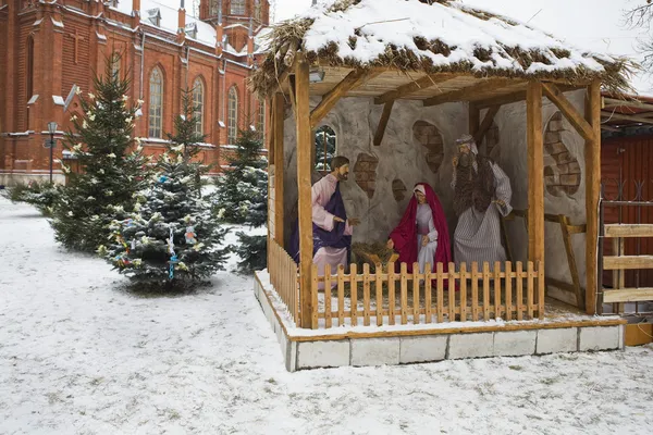Рождественская сцена: Иисус, Мария и Иосиф в яслях. Снежная улица возле церкви — стоковое фото