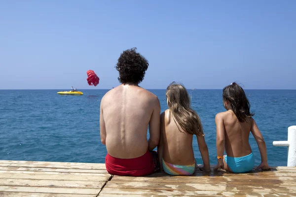 Pai com filhas estão sentados em cais — Fotografia de Stock