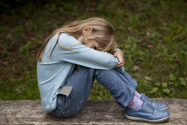 Flicka sitter på bänk i parken — Stockfoto