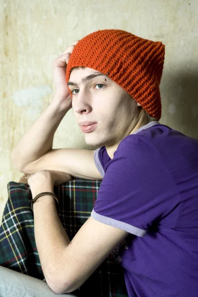 Portrait of serious young man in red hat sitting at old wall Royalty Free Stock Photos