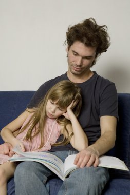Baba ve kız kanepede oturan ve bir kitap okuma
