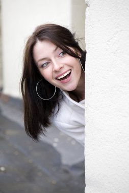 attractive young woman  peeking around the corner at house  clipart