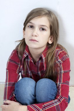 halı üzerinde oturan mutsuz kız.