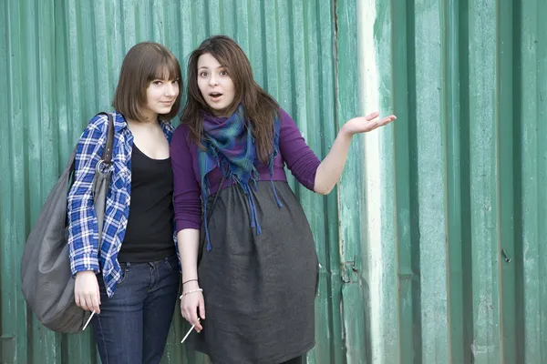 Two smoking girls standing at the fence — Stock Photo, Image