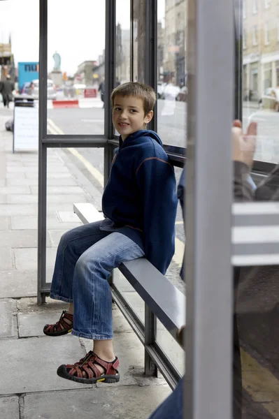 Chlapec seděl na autobusové zastávce — Stock fotografie