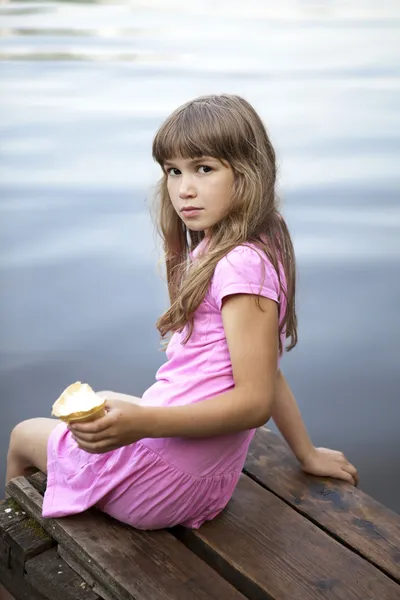 女孩坐在旧桥附近河 — 图库照片