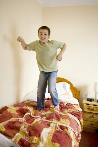 Piccolo ragazzo carino sta saltando sul letto — Foto Stock