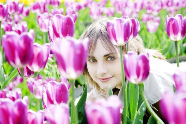 Junge glückliche Frau liegt in einem Tulpenfeld — Stockfoto